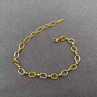 Gold and silver two-tone chain bracelet with oval links and lobster clasp on textured gray background